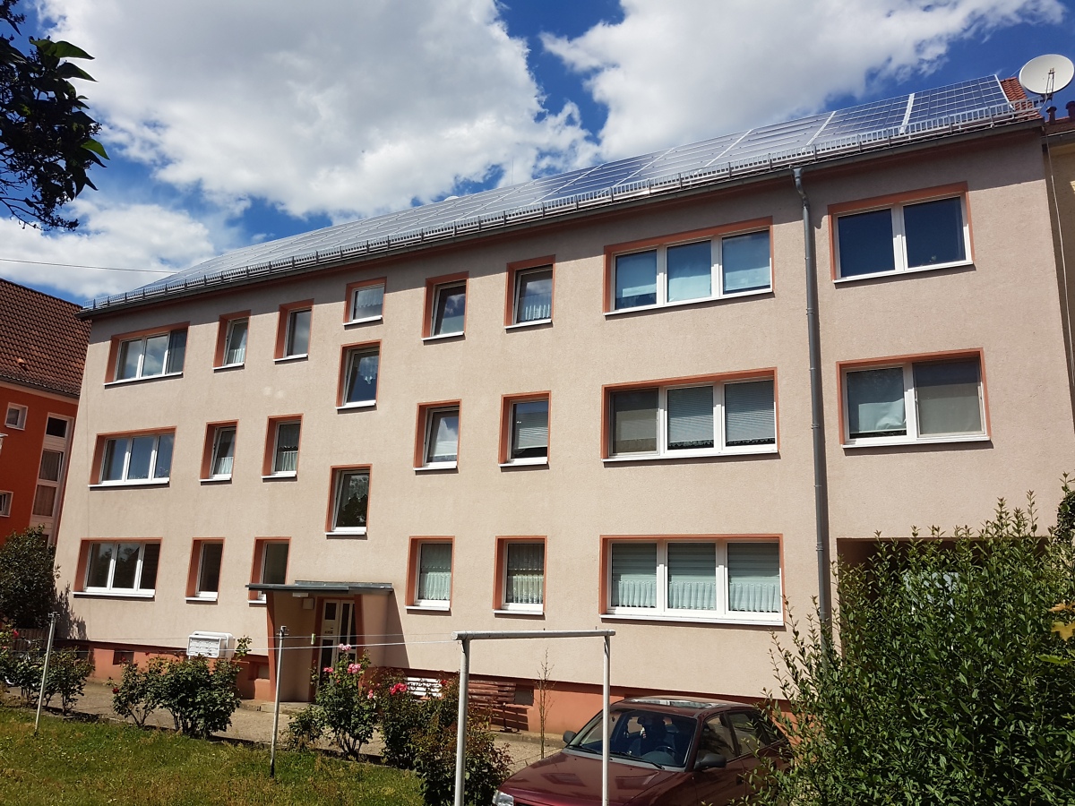 Ansicht eines dreistöckigen sanierten Mehrfamilienhauses vom grünen Innenhof aus