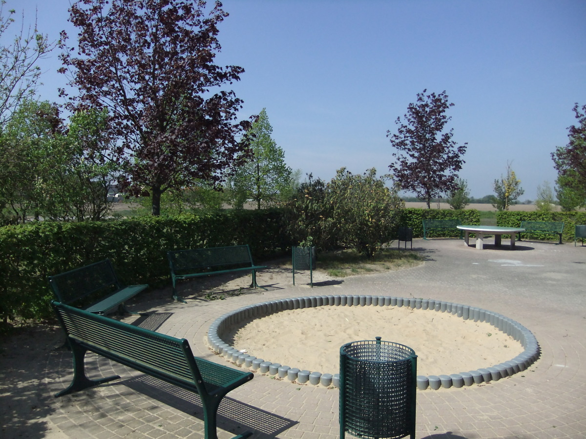 Blick auf einen Spielplatz mit Sandkasten mit Bänken im grünen Grundstück